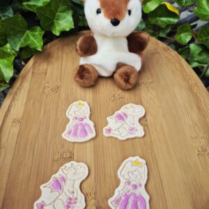 Pawinces & the Dragon hondenkoekjes uit de Once Upon a Treat collectie met prinses- en draakvormige koekjes op een houten plank naast een schattige hertjesknuffel.