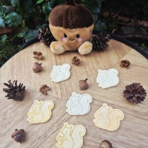 Ankie the Squirrel hondenkoekjes in de vorm van een vrolijke eekhoorn, tussen eikels en dennenappels.