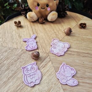 Forest Furriends Furrever hondenkoekjes in de vorm van een konijn, muis, uil en vos, in roze en paarse tinten, gepresenteerd op een houten tafel met eikels en dennenappels in een sfeervolle herfstsetting.